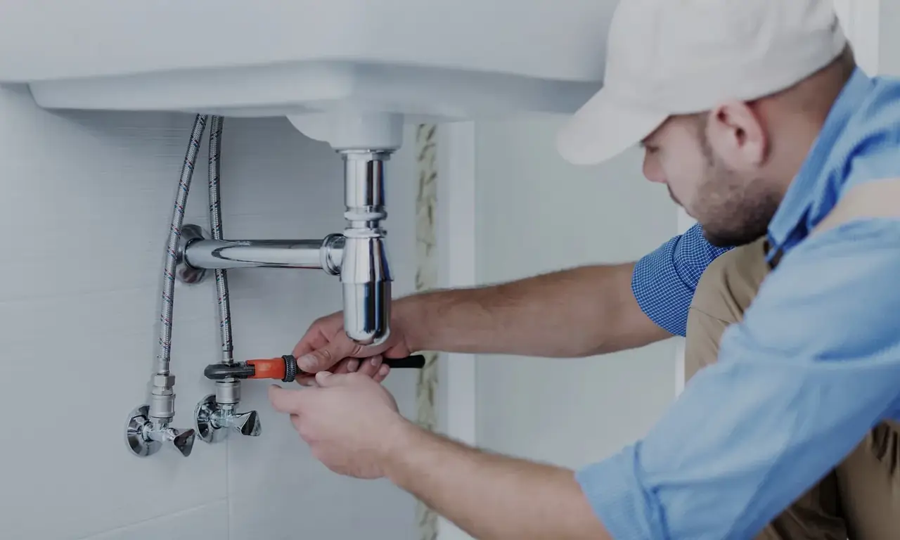 Licensed plumber repairing pipes under a kitchen sink